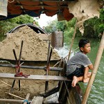 Nguyen Van To, 12, takes a break from shovelling sand as his father steers their boat to the sand collection point along the banks of Perfume River. -- CAROLINE CHIA/THE STRAITS TIMES 