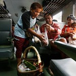 Ms Phai, a food vendor, selling fermented mince pork to passengers on a train before it pulls out of the station. -- CAROLINE CHIA/THE STRAITS TIMES